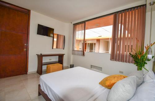 a bedroom with a white bed and a window at Hotel Mónaco Armenia in Armenia