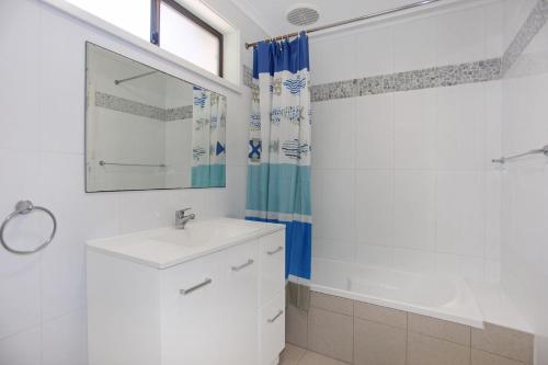 a white bathroom with a sink and a tub at Barralong Beach House in Hawks Nest