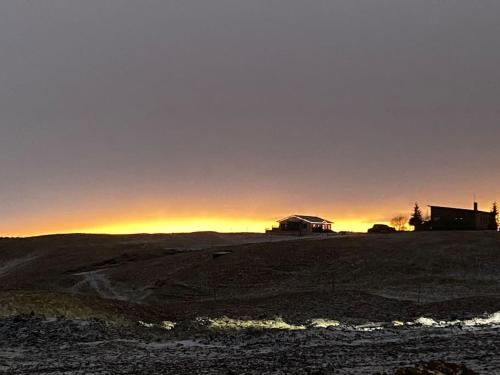 a house on a hill with the sunset in the background at Eaglerock Guesthouse and tours in Kirkjubæjarklaustur