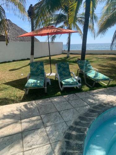 two chairs and an umbrella next to a swimming pool at Monterrico Casablanca in Chiquimulilla