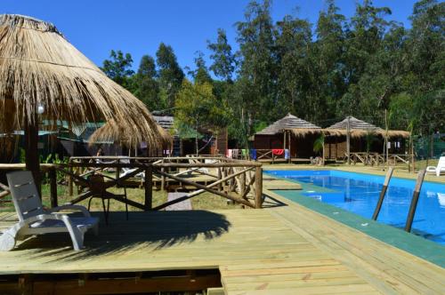 a resort with a pool and a deck with a chair and umbrella at Hostel del Barranco in La Pedrera