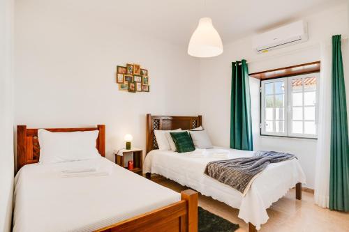 two beds in a room with green curtains at Lugar do Regato - Alojamento Local in Portel