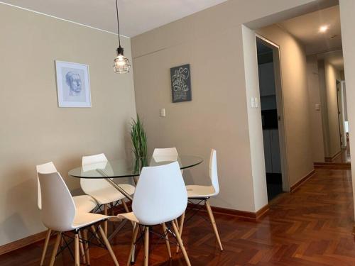 a dining room with a glass table and white chairs at MLA apartments - Kennedy in Lima