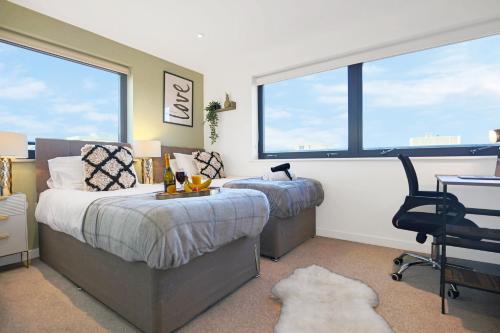a bedroom with two beds and a desk and a chair at Luxury Penthouse Apartment - Central MK - Pool Table, Balcony, Fast WiFi, Free Parking and Smart TVs with Sky TV and Netflix by Yoko Property in Milton Keynes