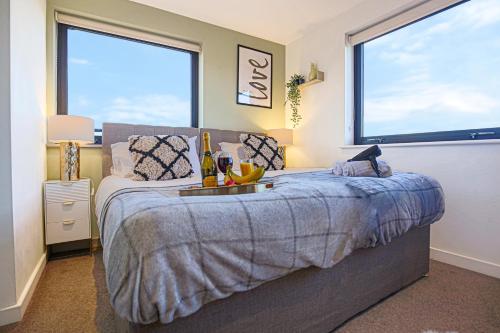a bedroom with a bed and two large windows at Luxury Penthouse Apartment - Central MK - Pool Table, Balcony, Fast WiFi, Free Parking and Smart TVs with Sky TV and Netflix by Yoko Property in Milton Keynes