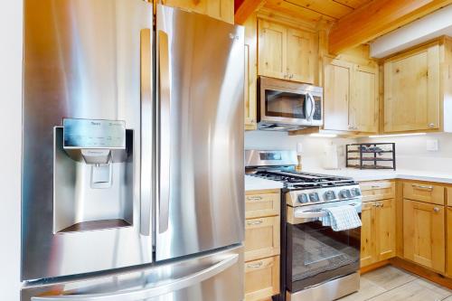 a stainless steel refrigerator in a kitchen with wooden cabinets at Hemlock Haven in Lake Arrowhead