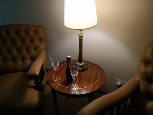 a lamp and two glasses on a table next to a chair at 4 Ventanales sobre la Avenida Corrientes in Buenos Aires