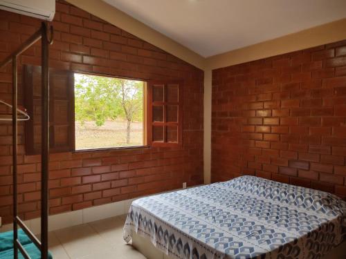 a bedroom with a bed and a window at Pousada Carmel Garden in Pirenópolis