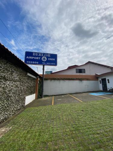 a blue sign in a parking lot next to a building at Berlor Airport Inn in Alajuela City