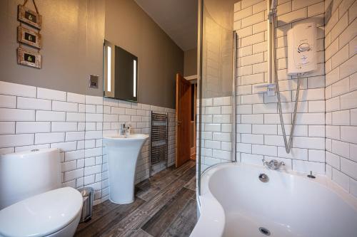 a bathroom with a tub and a toilet and a sink at Jardine Apartment @ Cairn Dhu House in Stornoway