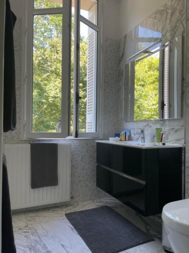La salle de bains est pourvue d'un lavabo, de toilettes et de 2 fenêtres. dans l'établissement La Villa Bocage, à Bordeaux