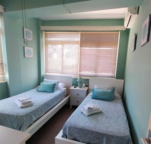 Duas camas num quarto com paredes e janelas azuis em Best location 2 bed2 bath w/lift in town! (Kosher) em Gibraltar