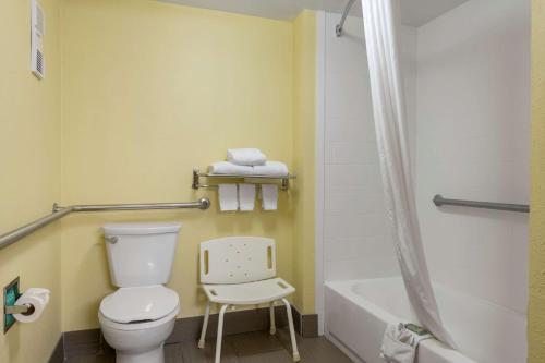 a bathroom with a toilet and a tub and a chair at Best Western Louisville East Inn & Suites in Louisville