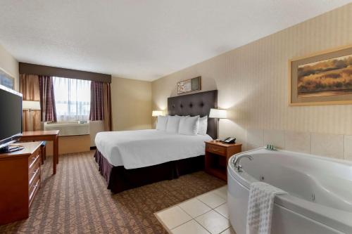 Cold LakeにあるBest Western Cold Lake Innのベッドとバスタブ付きのホテルルームです。