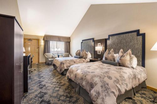 a hotel room with three beds and a television at Best Western Windsor Inn in Ashland