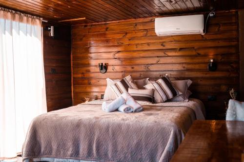 a bedroom with a bed with a wooden wall at Cabanas Invernada de Cima in São Joaquim