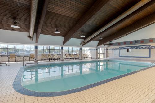 a large swimming pool in a large room with chairs and tables at Best Western Plus Dryden Hotel and Conference Centre in Dryden