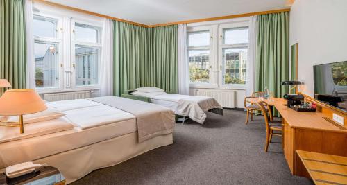 a hotel room with two beds and a desk at Best Western Hotel Moran in Prague