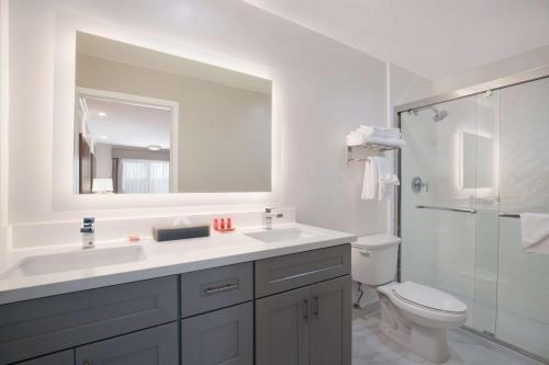 a bathroom with a sink and a toilet and a mirror at SureStay Plus Hotel by Best Western Upland - Ontario North in Upland
