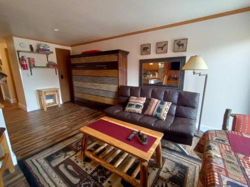 a living room with a leather couch and a table at Alex's Cozy STUDIO with Pool and Sauna in Brian Head