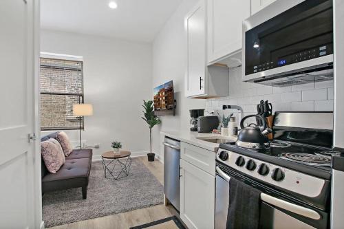 a kitchen with a stove top oven next to a couch at Studio Apt with Laundry, Near Shops! - Montrose Studio rep in Chicago
