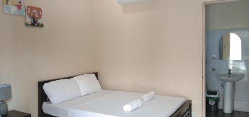 um quarto branco com uma cama e um lavatório em Claytown Pension House em Dumaguete