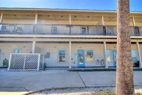 an apartment building with a balcony and a palm tree at Family Tides Beach House in Port Aransas