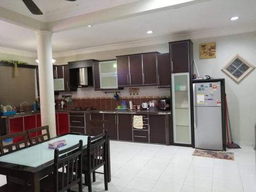 a kitchen with a table and a refrigerator at SRI WANG HOMESTAY @ ARAU in Arau