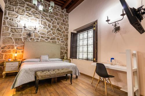 1 dormitorio con cama y pared de piedra en Hotel Cantera Rosa, en Morelia
