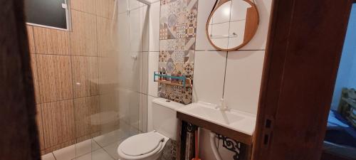 a bathroom with a toilet and a sink and a mirror at Morada das Orquídeas in Guarda do Embaú