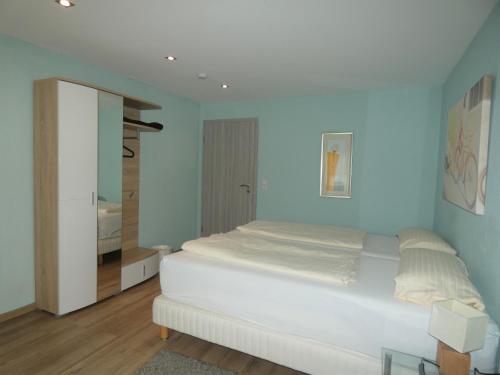 a bedroom with a white bed and a blue wall at Hotel Yel in Ludwigshafen am Rhein