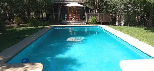 a swimming pool with blue water in a yard at Cabaña Lodge los Coihues VALLE LAS TRANCAS# TERMAS DE CHILLAN#NEVADOS DE CHILLAN in Pinto