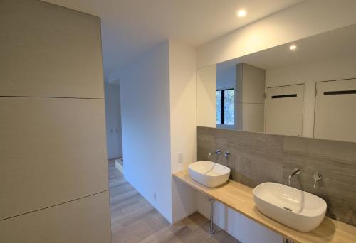 Baño con 2 lavabos y espejo en Myoko Apartments en Akakura