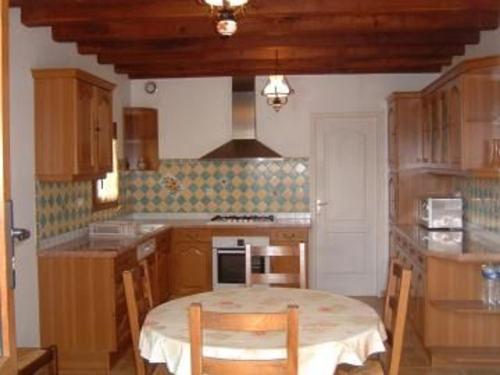 une cuisine avec une table et des chaises dans une pièce dans l'établissement Gîte spacieux et paisible près du Mans avec grand terrain, 15 couchages, ping-pong et WIFI - FR-1-410-178, à Chaufour-Notre-Dame