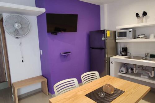 a kitchen with a table and a purple wall at Morado Departamento 42 m2 CIVAC,NISSAN Y WALMART. in Jiutepec