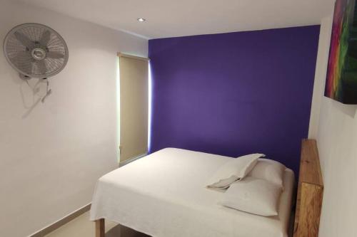 a bedroom with a white bed and a purple wall at Morado Departamento 42 m2 CIVAC,NISSAN Y WALMART. in Jiutepec