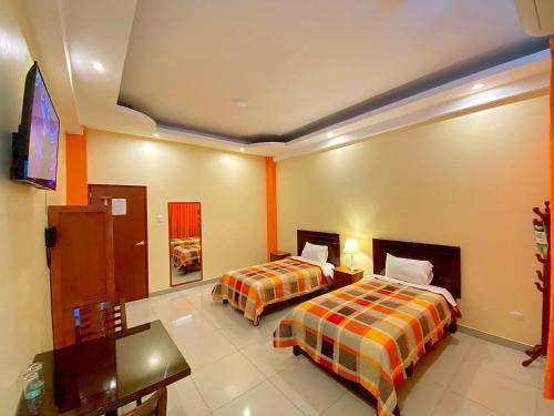 a hotel room with two beds and a flat screen tv at Hotel Las Palmeras in Huacho
