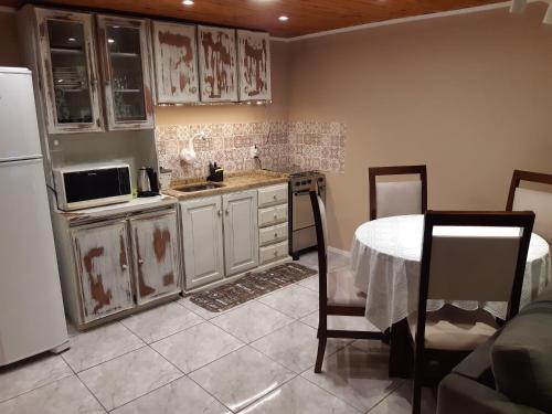 a kitchen with a table and a white refrigerator at Rifugio del Camino - Chalé Completo in Gramado