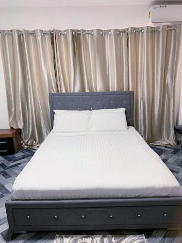 a bed in a room with a bed frame and curtains at Lovely 1-bedroom rental unit for short stays. in Tema