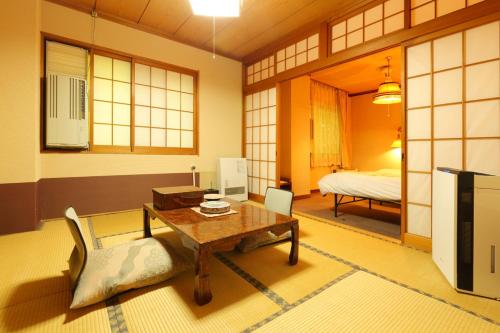 uma sala de estar com uma mesa e uma cama em Dai Onsen Matsudaya Ryokan em Hanamaki