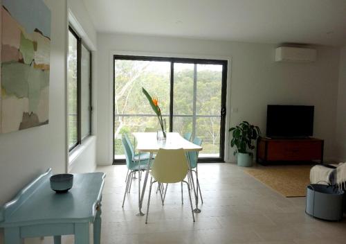 a living room with a table and chairs and a large window at Peaceful bush retreat in newly renovated lodge in St Andrews in Saint Andrews