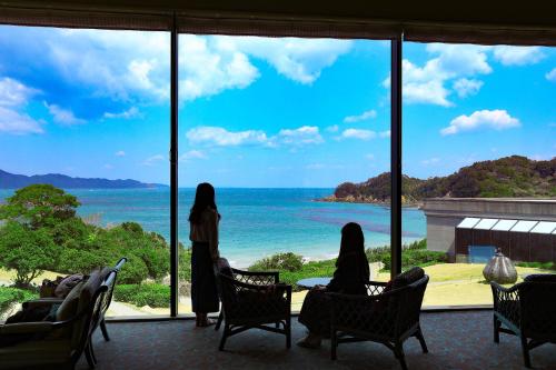 Dos mujeres de pie en una habitación mirando al océano en TAOYA Shima, en Toba