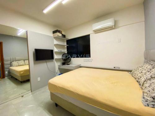 um quarto de hotel com uma cama e uma televisão em Apt. encantador 50m da praia de Ponta Verde em Maceió