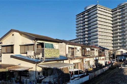 a building with two tall buildings next to a river at 江ノ島に近い富士山も眺めるまるまる貸切一軒家ーーー湘南の丘のヴィラ in Fujisawa