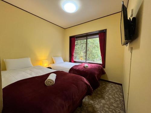 a hotel room with two beds and a window at Lodge Q in Hakuba