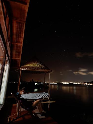 a person sitting on a chair on the dock at night at Uros Walysuma Titicaca Lodge in Puno
