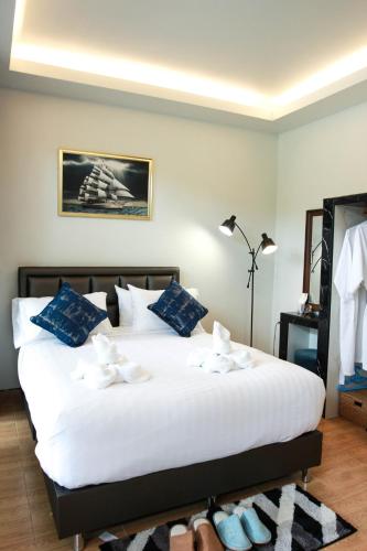 a bedroom with a large white bed with blue pillows at Phetrapoolvilla (เภตราพูลวิลล่า) in Surat Thani