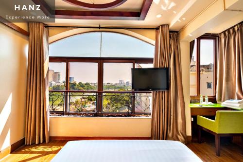 a bedroom with a large window with a bed and a desk at HANZ LakeView Hotel Hanoi in Hanoi