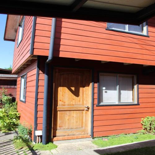 Casa roja con puerta y ventanas de madera en Cabañas Familiares "Frida", en Valdivia