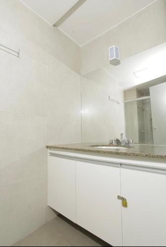 a white bathroom with a sink and a mirror at Apartamento 1009 in Goiânia